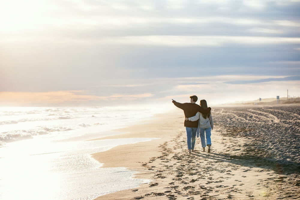 A couple walking along the beach on a Florida winter vacation to Panama City Beach.